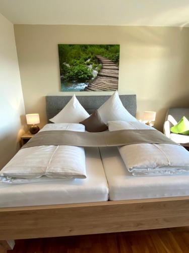 a bed with white pillows and a painting on the wall at Hotel Landhaus Sternen in Sipplingen