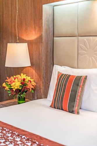 a bed with a vase of flowers and a lamp at The Park New Delhi in New Delhi