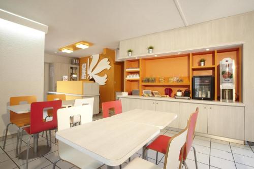 a kitchen and dining room with a table and chairs at Premiere Classe Avignon Courtine Gare TGV in Avignon