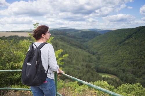 a woman with a backpack standing on top of a mountain at Landhaus Heimisch Bed & Breakfast in Geisfeld