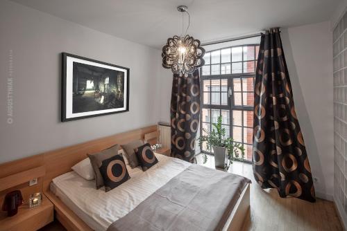a bedroom with a bed and a window with a chandelier at LOFT APARTMENTS in Łódź