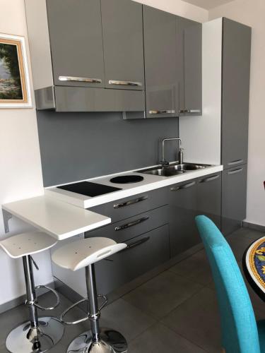 a kitchen with stainless steel cabinets and blue chairs at Hotel CineApollo - Ogni camera un film! in Messina