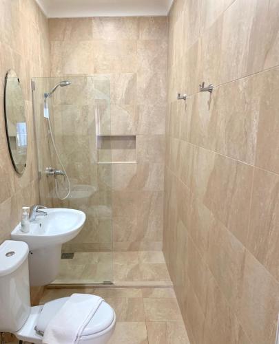a bathroom with a toilet and a shower and a sink at Sands Apartments in St Paul's Bay