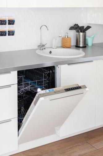 a dishwasher in a white kitchen with a sink at 3 Bedroom Apartment 24h self check in, free parking, Ac, fireplace in Vilnius