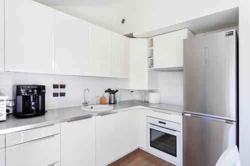 a kitchen with white cabinets and a stainless steel refrigerator at 3 Bedroom Apartment 24h self check in, free parking, Ac, fireplace in Vilnius