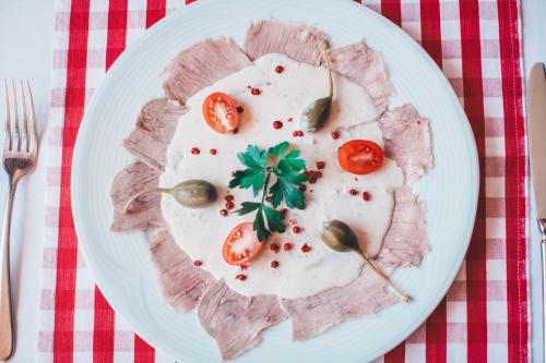a plate of food with meat and tomatoes on it at Hotel und Pension Al Dente in Nünchritz