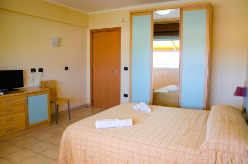 een slaapkamer met een bed, een televisie en een dressoir bij Eden Residence Club in Torre Ovo