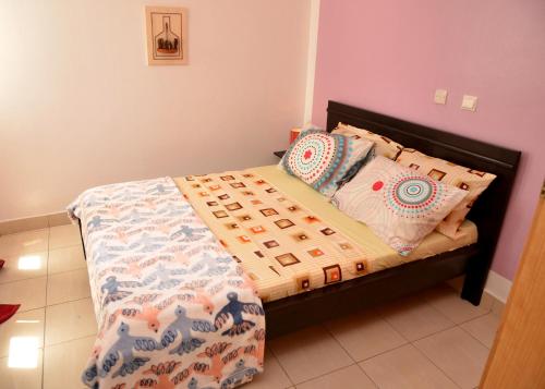 a bedroom with a bed with a comforter and pillows at Bel Appart F3, Koumassi, proche aéroport d'Abidjan in Koumassi
