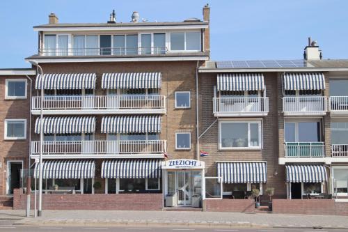 Appartementen Zeezicht - 3 في Katwijk aan Zee: عمارة سكنية عليها مظلات بيضاء