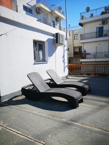 Deux chaises assises sur le côté d'un bâtiment dans l'établissement Explore Greece from Cozy City Centre Apartment, à Chalcis