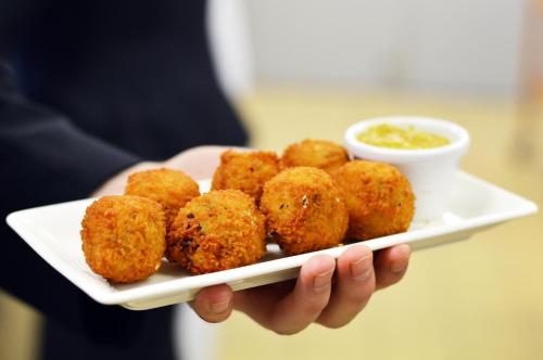 a person holding a plate with food on it at Skotel The Hague, Hotelschool The Hague in Scheveningen