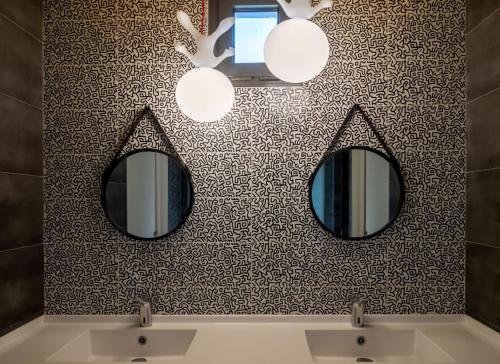 een badkamer met twee spiegels aan een muur bij Sous Les Pins in Étoile-sur-Rhône