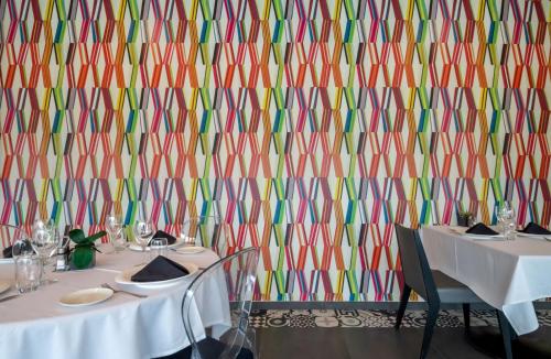 a room with two tables and a colorful wall at Sous Les Pins in Étoile-sur-Rhône