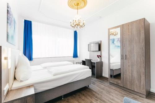 a bedroom with a white bed and white walls at Haus am Dom - Apartments und Ferienwohnungen in Cologne