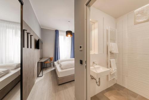 uma pequena casa de banho com um lavatório e uma cama em Smart Stay Hotel Station em Munique