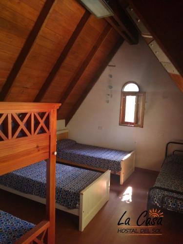 a attic room with three bunk beds and a window at La casa de Hostal del Sol in Rosario