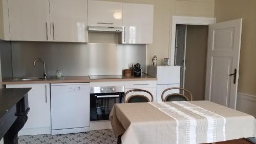 uma cozinha com armários brancos e uma mesa com um sidx sidx em Appart'hotel de la Mairie em Morlaix