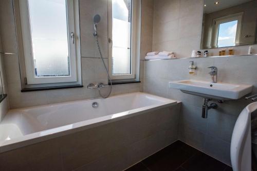 a bathroom with a bath tub and a sink at Flonk Hotel Groningen Centre, BW Signature Collection in Groningen