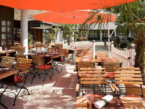 an outdoor restaurant with tables and chairs and an umbrella at Mercure Hotel am Messeplatz Offenburg in Offenburg