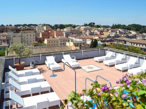 a rooftop patio with white lounge chairs on a building at Mercure Roma Centro Colosseo in Rome