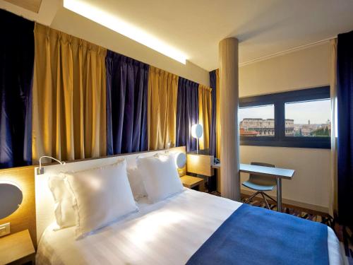 ローマにあるメルキュール ローマ セントロ コロッセオのベッドとデスクが備わるホテルルームです。