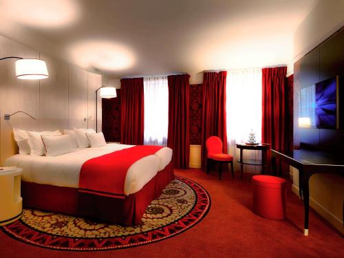 リヨンにあるHotel Carlton Lyon - MGallery Hotel Collectionの大きなベッドとデスクが備わるホテルルームです。