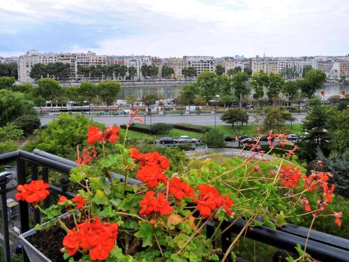 a view of a city from a balcony with red flowers at Mercure Paris Tour Eiffel Pont Mirabeau in Paris