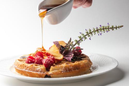 a plate of waffles with fruit and syrup on it at The Tides Inn in West Irvington