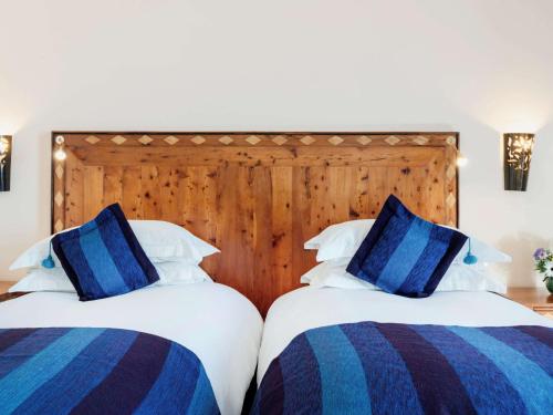 two beds with blue and white pillows in a bedroom at Le Médina Essaouira Thalassa Sea & Spa - MGallery Collection in Essaouira