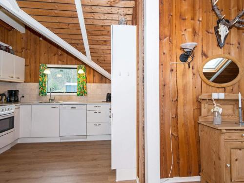 a kitchen with white cabinets and a wooden wall at 6 person holiday home in Toftlund in Arrild