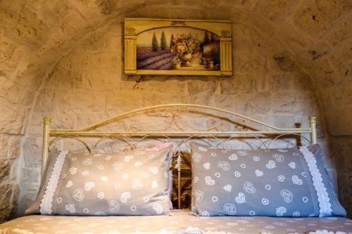 a bed with two pillows and a picture on the wall at Il trullo del Mirto in Selva di Fasano