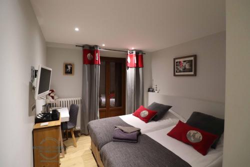 a bedroom with a bed with red pillows and a desk at Hotel la Turra in Termignon