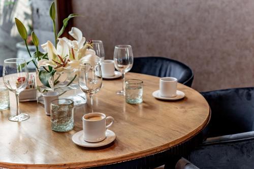 a wooden table with plates and glasses and flowers on it at Casa Raíces Hotel Luxury & Viñedo in Los Galvanes