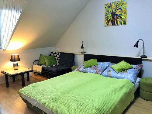 sypialnia z zielonym łóżkiem i kanapą w obiekcie Kishableány Apartmanház w mieście Badacsonytomaj
