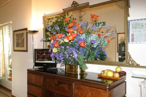 a vase of flowers on a dresser in front of a mirror at Hotel Panorama Bologna Centro in Bologna