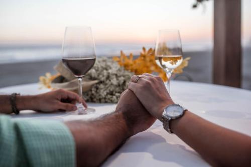 una persona sentada en una mesa con dos copas de vino en Hotel Tres Vidas Acapulco, en Barra Vieja