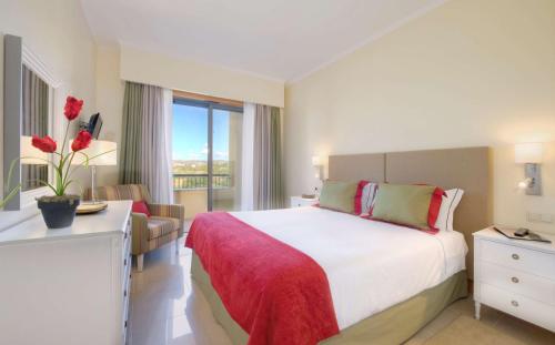 a hotel room with a bed and a dresser at The Residences at Victoria by Tivoli in Vilamoura