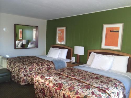 two beds in a hotel room with green walls at Alamo Motel in Sheridan