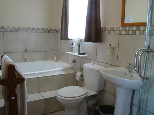a bathroom with a toilet and a sink and a tub at Aqua Marine Guest House in Port Elizabeth