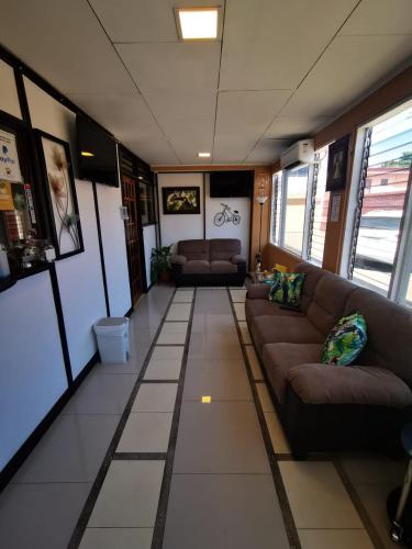 a living room with couches and tables in a room at Toucan Hostel in Alajuela City