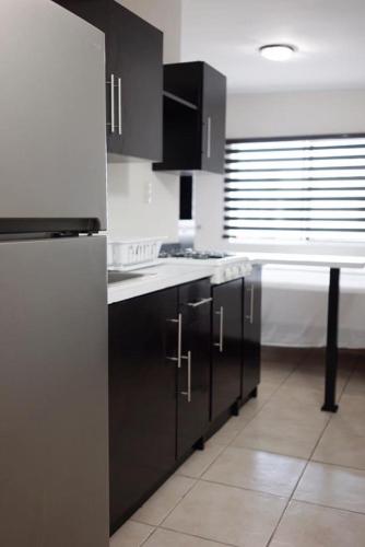 une cuisine avec des armoires noires et des comptoirs blancs dans l'établissement Hotel Diez, à Tampico