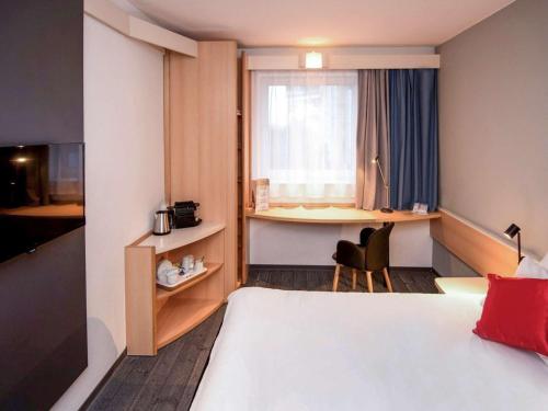 a hotel room with a bed and a desk and a window at Ibis Poznan Stare Miasto in Poznań