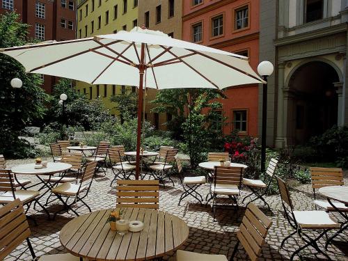 a patio with tables and chairs and an umbrella at Mercure Hotel & Residenz Berlin Checkpoint Charlie in Berlin
