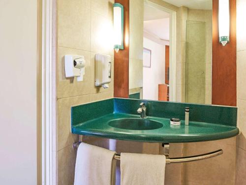 La salle de bains est pourvue d'un lavabo vert et d'un miroir. dans l'établissement Ibis Monterrey Aeropuerto, à Monterrey