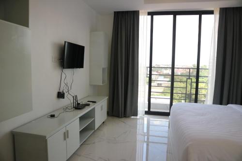a white hotel room with a bed and a balcony at LY Residence Suite & Apartment in Siem Reap
