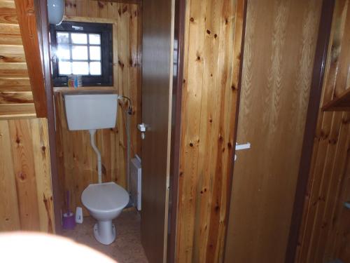 a bathroom with a toilet and a window and wooden walls at Penzion Mikeš in Pec pod Sněžkou