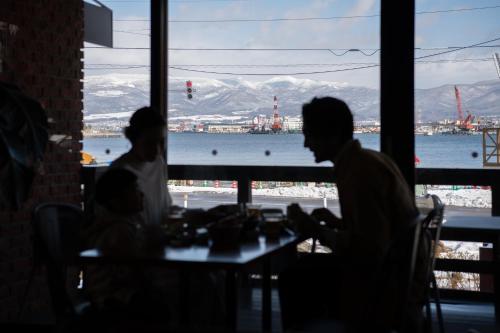 two people sitting at a table looking out a window at HakoBA Hakodate by THE SHARE HOTELS in Hakodate
