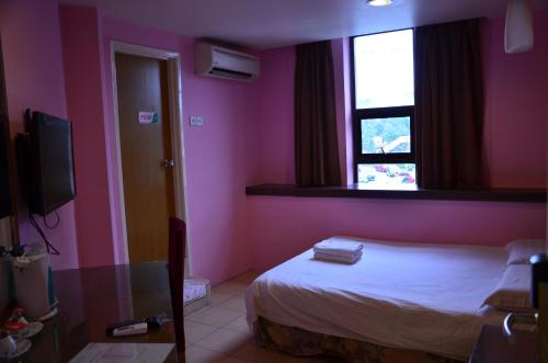 a bedroom with pink walls and a bed with a window at Uptown Hotel Kajang in Kajang