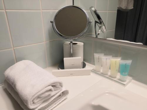 a bathroom with a sink with a mirror and towels at Hotel Kauppi in Tampere