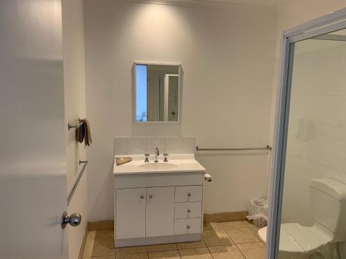 a bathroom with a sink and a toilet and a mirror at Heyfield Motel and Apartments in Lakes Entrance